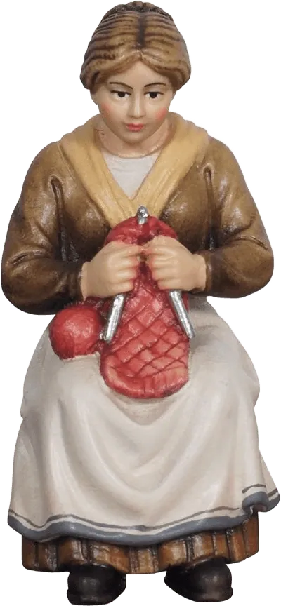 Hand-carved wooden figure of a seated grandmother knitting, painted in brown, cream, yellow and red